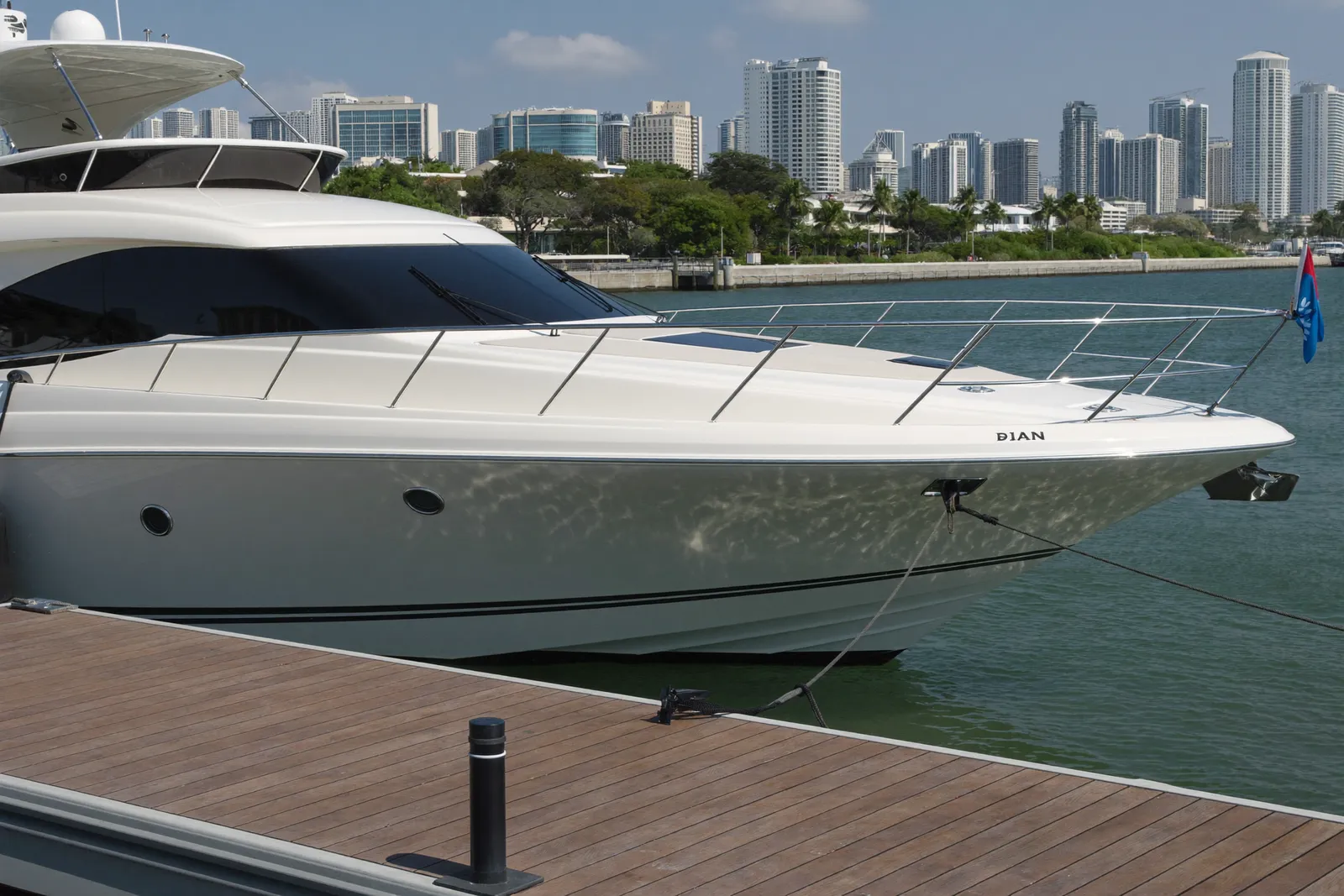 A motor yacht moored at a marina dock with the Miami skyline behind it